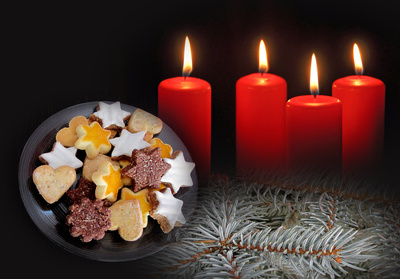 Vier brennende Adventskerzen und Gebäck