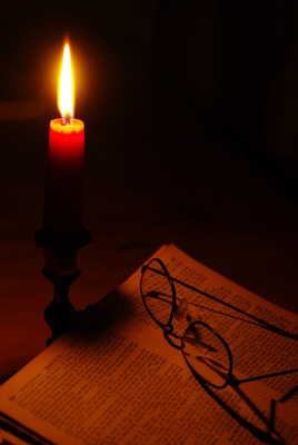 Eine brennende Adventskerze mit Brille