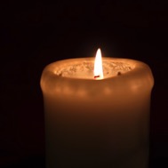 Eine brennende Adventskerze vor schwarzem Hintergrund Eine brennende Adventskerze vor schwarzem Hintergrund