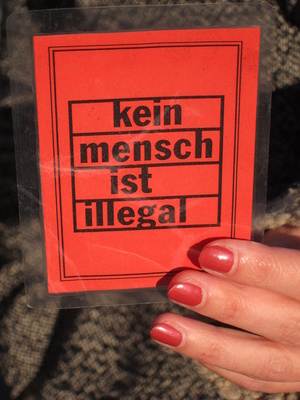 Frauenhand hält Zettel mit Aufschrift: Kein Mensch ist illegal
