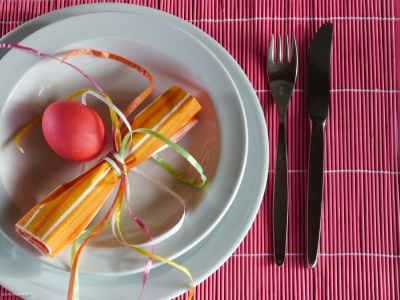 Mit rotem Ei und gestreifter Serviette dekoriertes Gedeck