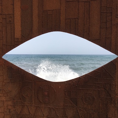 Metallwand mit Augenausschnitt und aufbrausendem Meer