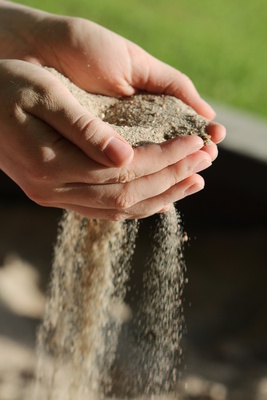 Hände aus denen Sand rieselt