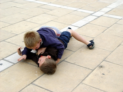 Sich am Boden balgende Jungs