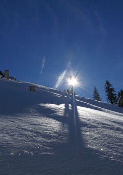 Gipfelkreuz im Gegenlicht und Schneelandschaft