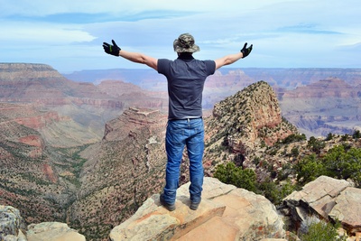 Mann mit geöffnetnen Armen auf einem Berg