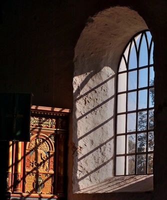 Sonnenstrahlen durch ein Kirchenfenster erleuchten den Raum und werfen Schatten der Fensterkreuze