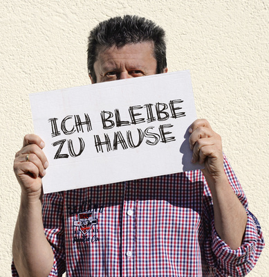 Mann mit Schild: ICH BLEIBE ZU HAUSE