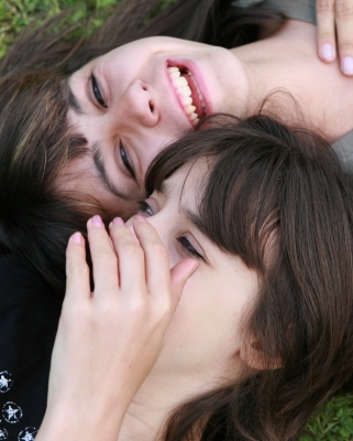 Zwei liegende Frauengesichter, eine hat eine Hand vor dem Mund