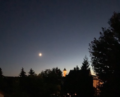 Abendstimmung mit Mond über einer Stadt