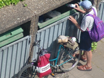 Person wühlt in einem Müllcontainer