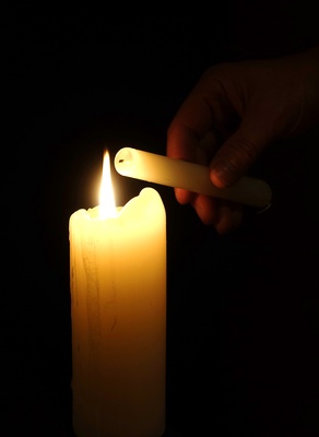 Leuchtende Kerze, an der eine andere Kerze angezündet wird