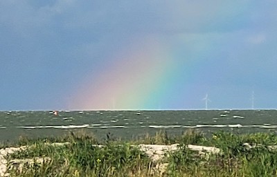 Regenbogen über dem Meer mit Düne im Vordergrund