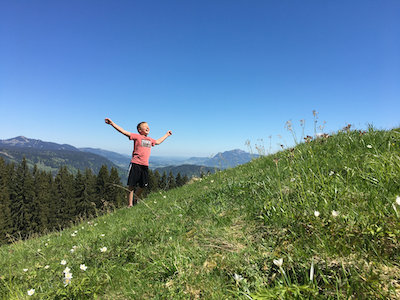 Kind mit ausgestreckten Armen auf einer Bergwiese Kind mit ausgestreckten Armen auf einer Bergwiese