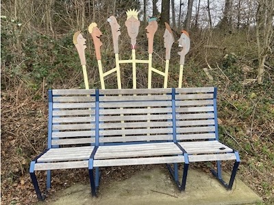 Bank mit 7 zueinander sprechenden Köpfen im Hintergrund