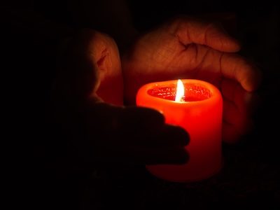 Kerze mit schützenden Händen