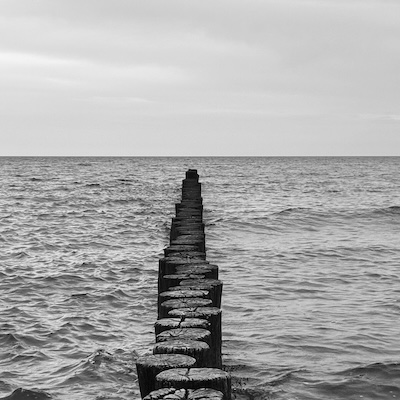 Schwarz-Weiß-Bild vom Meer mit Holzbohlen
